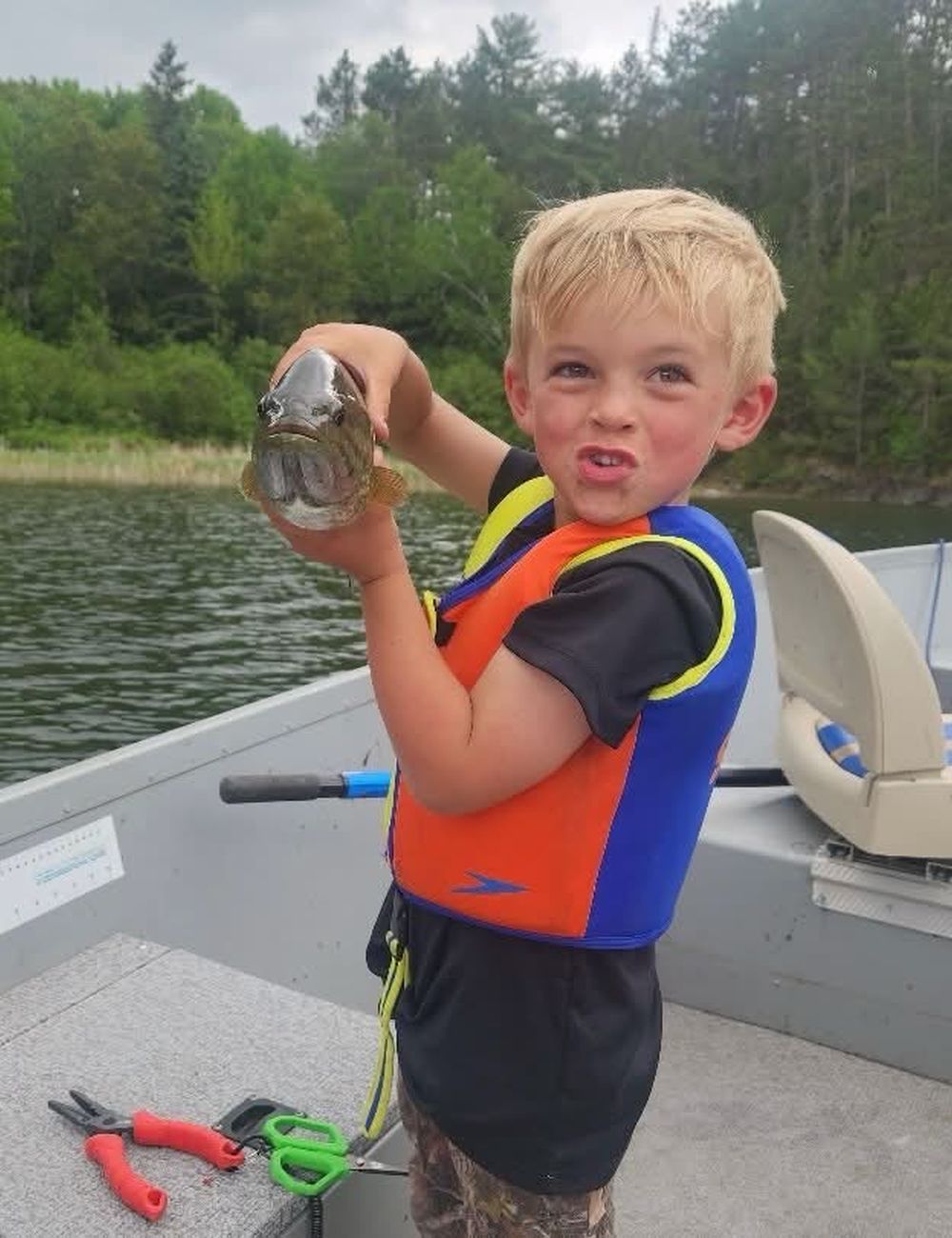 Young angler in a life jacket proud of his catch
